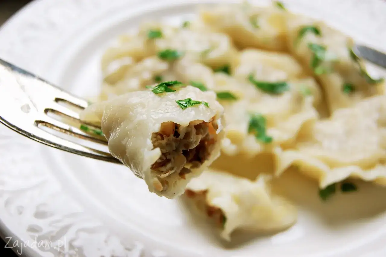 Pyszne pierogi z kaszą gryczaną, jeden na widelcu, z posiekaną natką pietruszki.