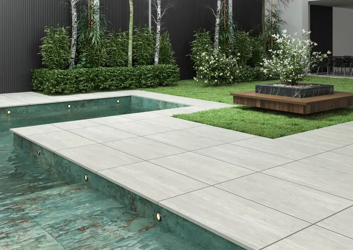 Piscina moderna con suelo antideslizante, el mejor suelo para exterior, rodeada de c&eacute;sped y vegetaci&oacute;n.