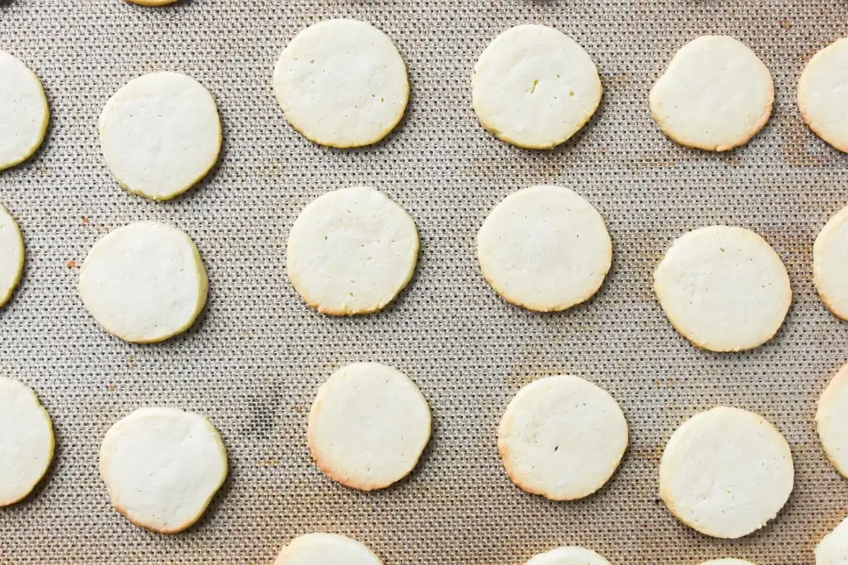Muchas galletas cookies redondas y doradas dispuestas en una bandeja para hornear.