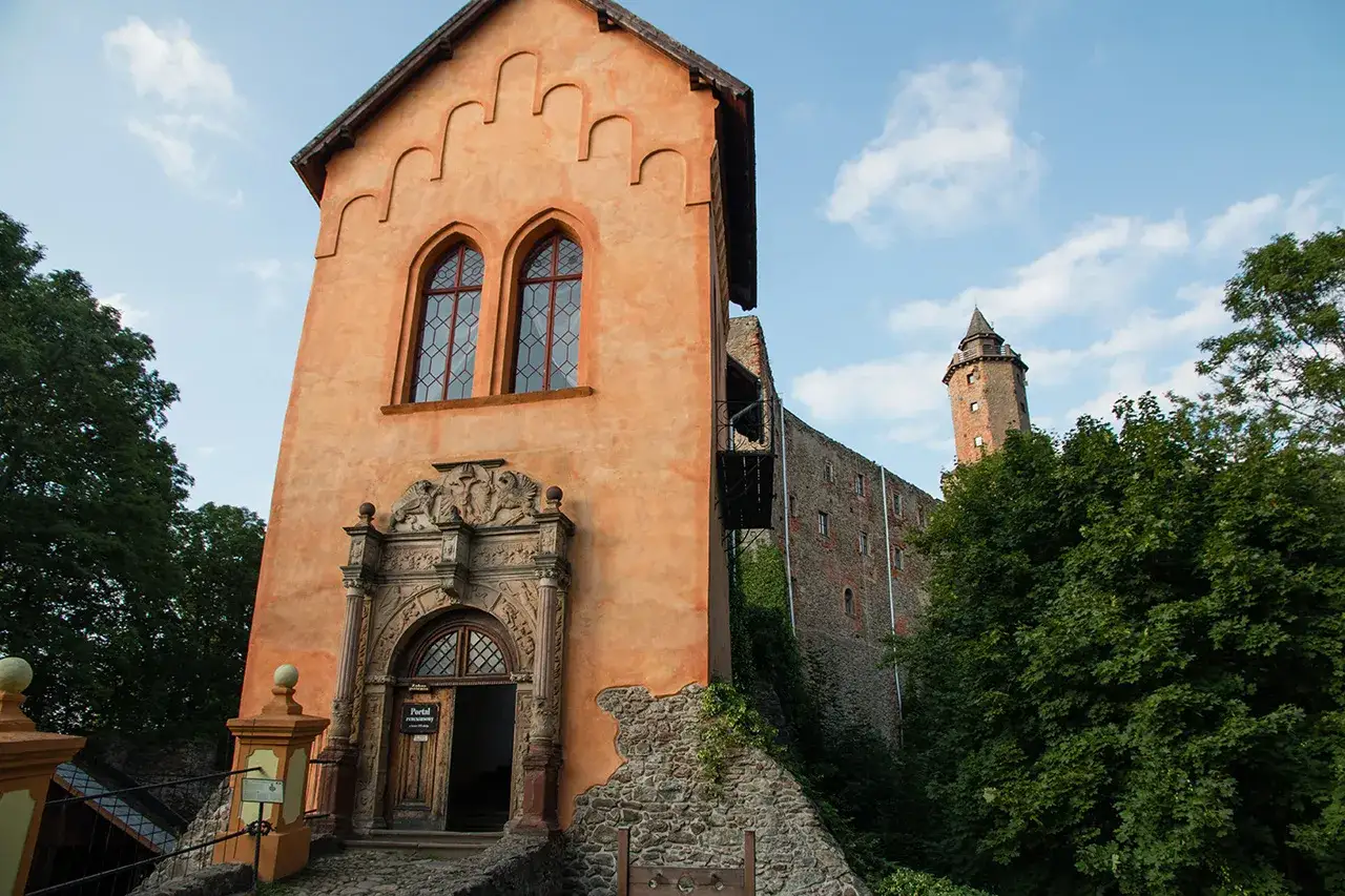 Zamek Książ, idealny na jednodniowe wycieczki z Wrocławia, z pomarańczową wieżą i kamiennym murem.