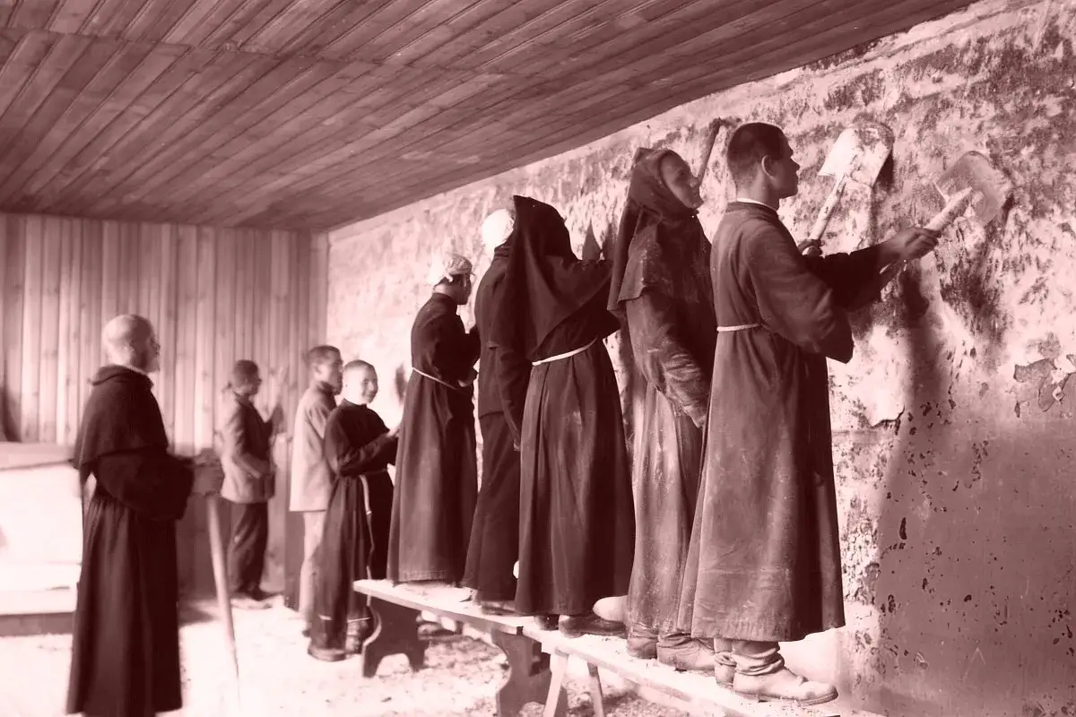 Maksymilian Kolbe ciekawostki: zakonnicy w habicie pracują przy ścianie, niektórzy z łopatami.