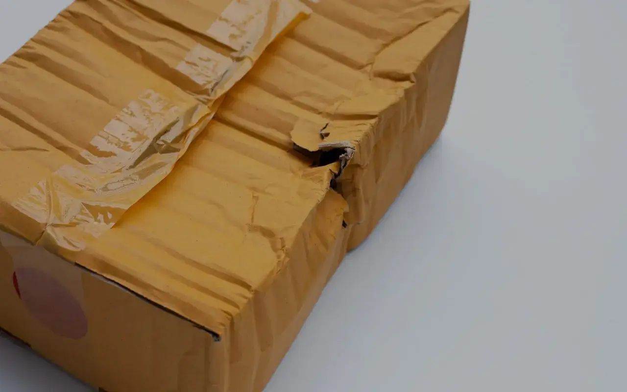 Carton brun abîmé, déchiré sur le côté, montrant un produit endommagé après déballage.