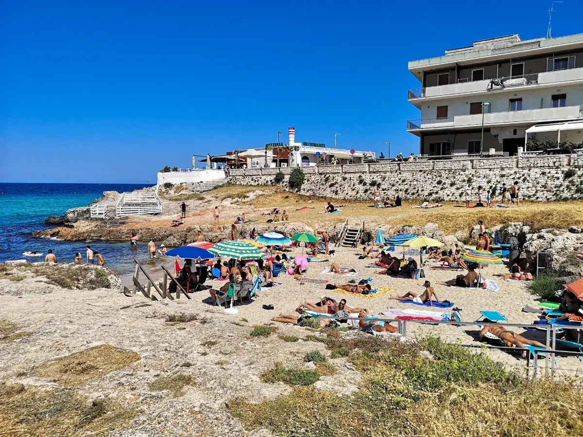 Słoneczny dzień na plaży, ludzie opalają się i kąpią w morzu. Wspaniałe bari atrakcje dla każdego.