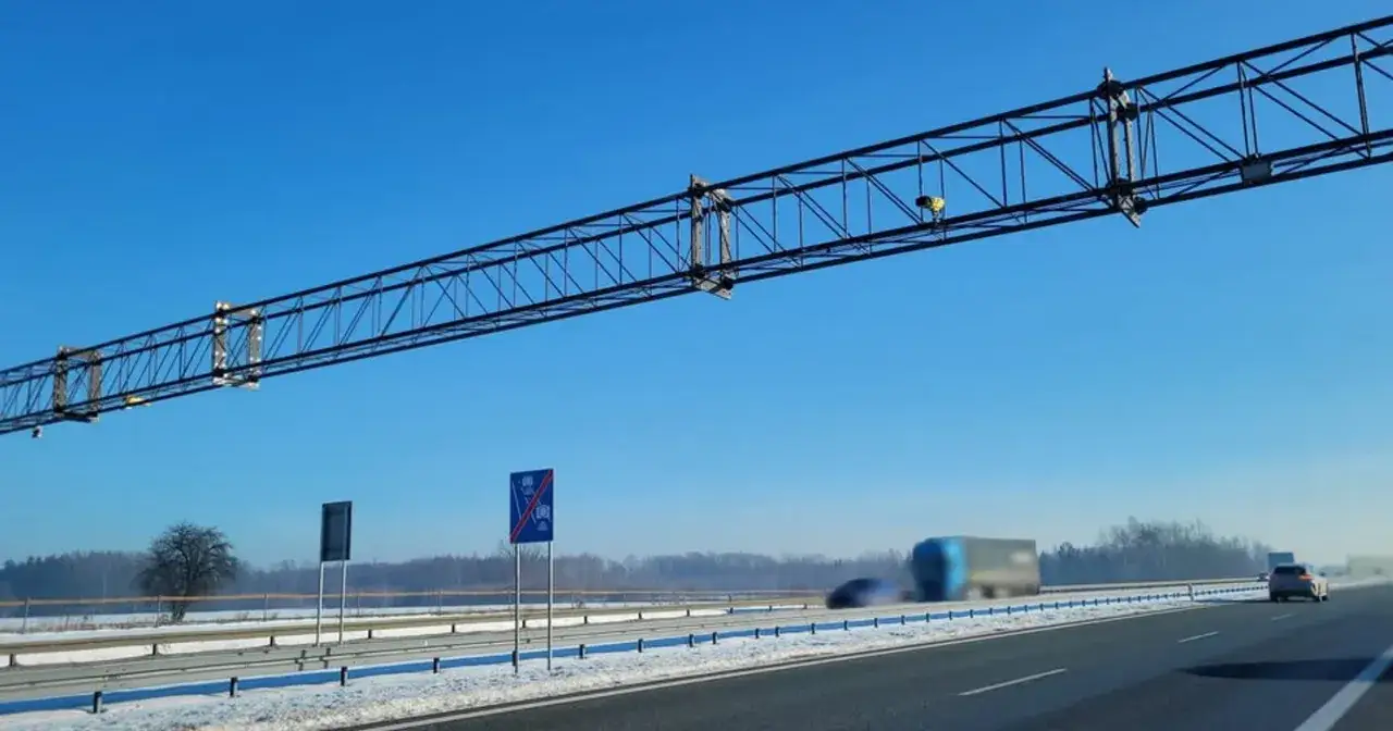 Stalowa konstrukcja nad drogą S8, zapowiadająca odcinkowy pomiar prędkości. W tle zimowy krajobraz i jadące pojazdy.