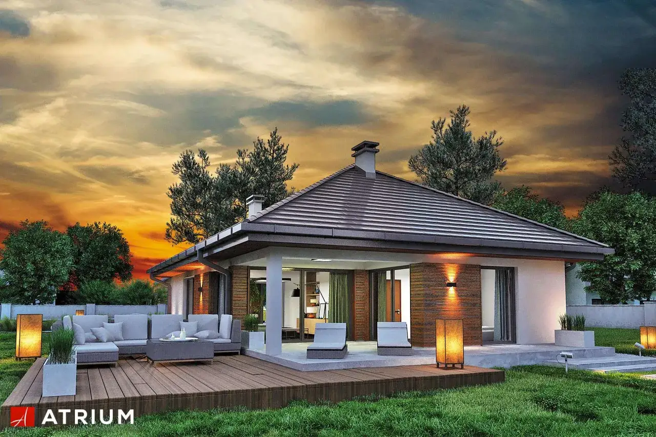Nowoczesny bungalow z tarasem i wygodnymi meblami wypoczynkowymi, otoczony zielenią. Zachód słońca maluje niebo na pomarańczowo.
