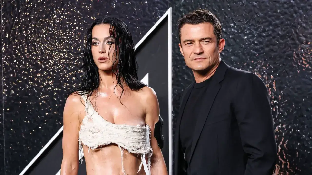 Katy Perry i Orlando Bloom na ściance. Ona w odważnej, postrzępionej kreacji, on w eleganckim garniturze.