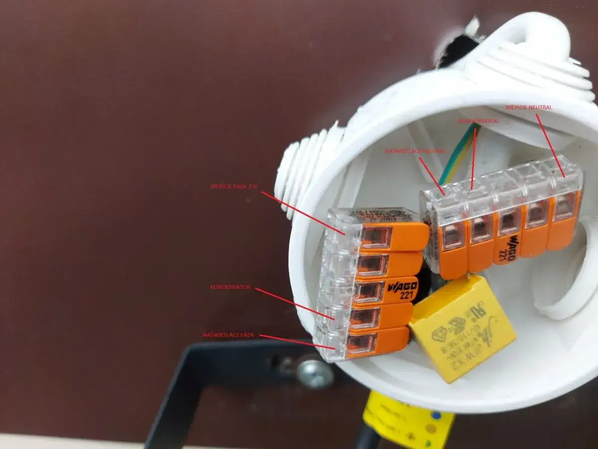 Włączona lampa led żarzy się, widoczne złącza WAGO, kondensator i przewody fazy i neutralny.