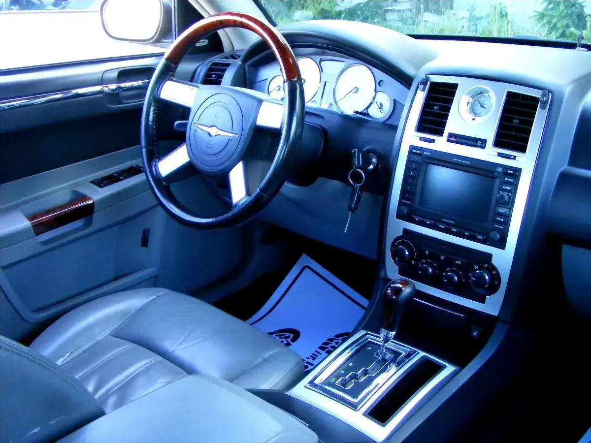 Wnętrze Chrysler 300S z wygodnymi skórzanymi fotelami, drewnianą kierownicą i nowoczesnym panelem multimedialnym.