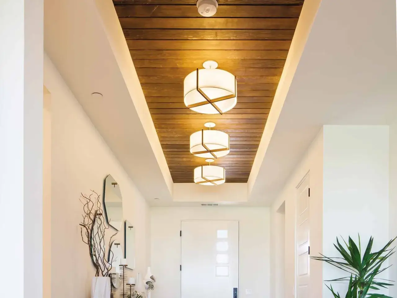 Nowoczesne oświetlenie przedpokoju z drewnianym sufitem i designerskimi lampami.