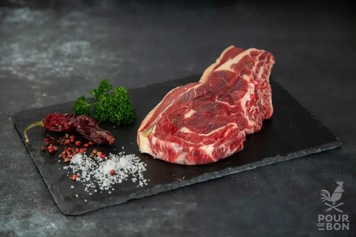 Belle entrecôte crue sur ardoise, avec persil, piments séchés et sel. Un délice à préparer.