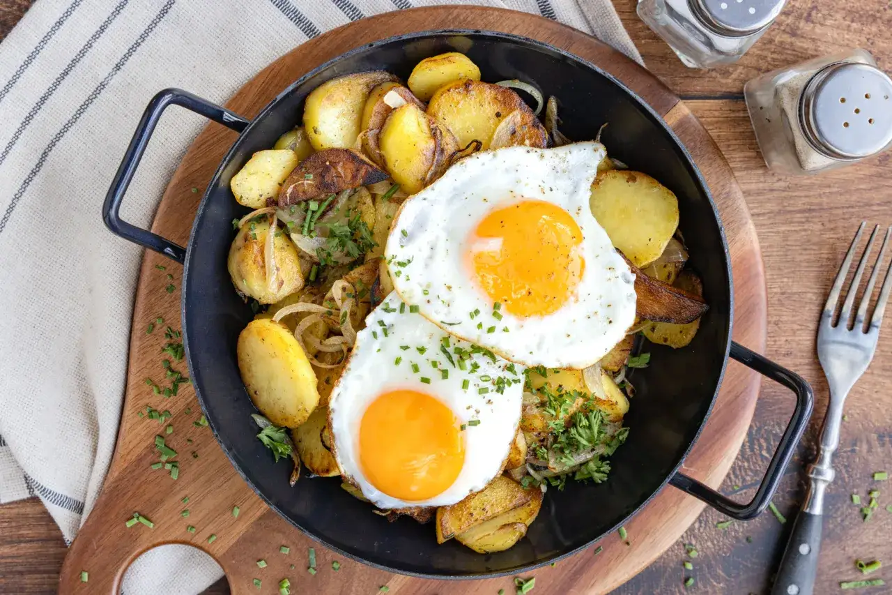 Herzhafte bratkartoffeln mit ei, garniert mit Petersilie und Schnittlauch. Ein Klassiker, der immer schmeckt.
