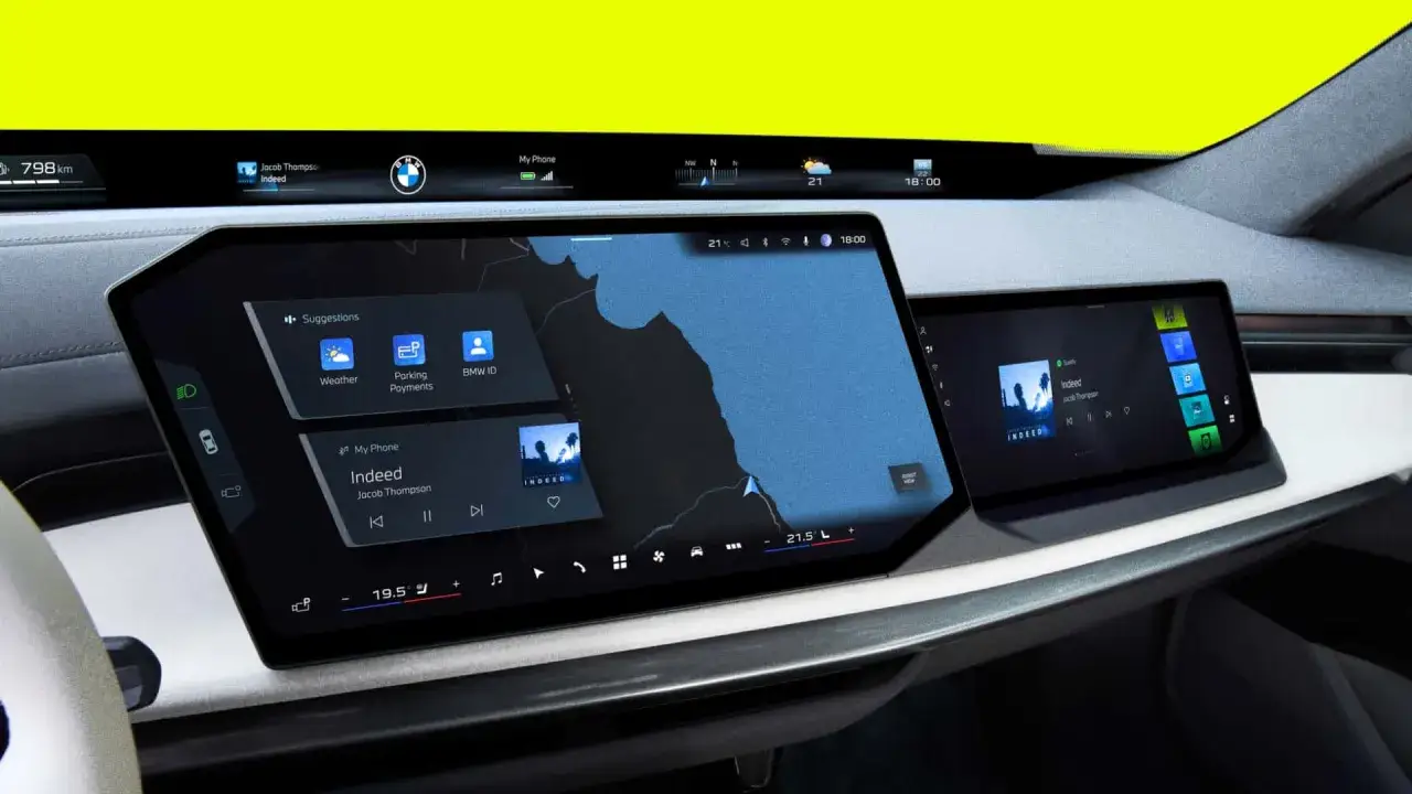 Nowoczesny kokpit BMW z dwoma ekranami. Na głównym wyświetlaczu mapa i sugestie, na bocznym muzyka. Jacob Thompson korzysta z funkcji Indeed.