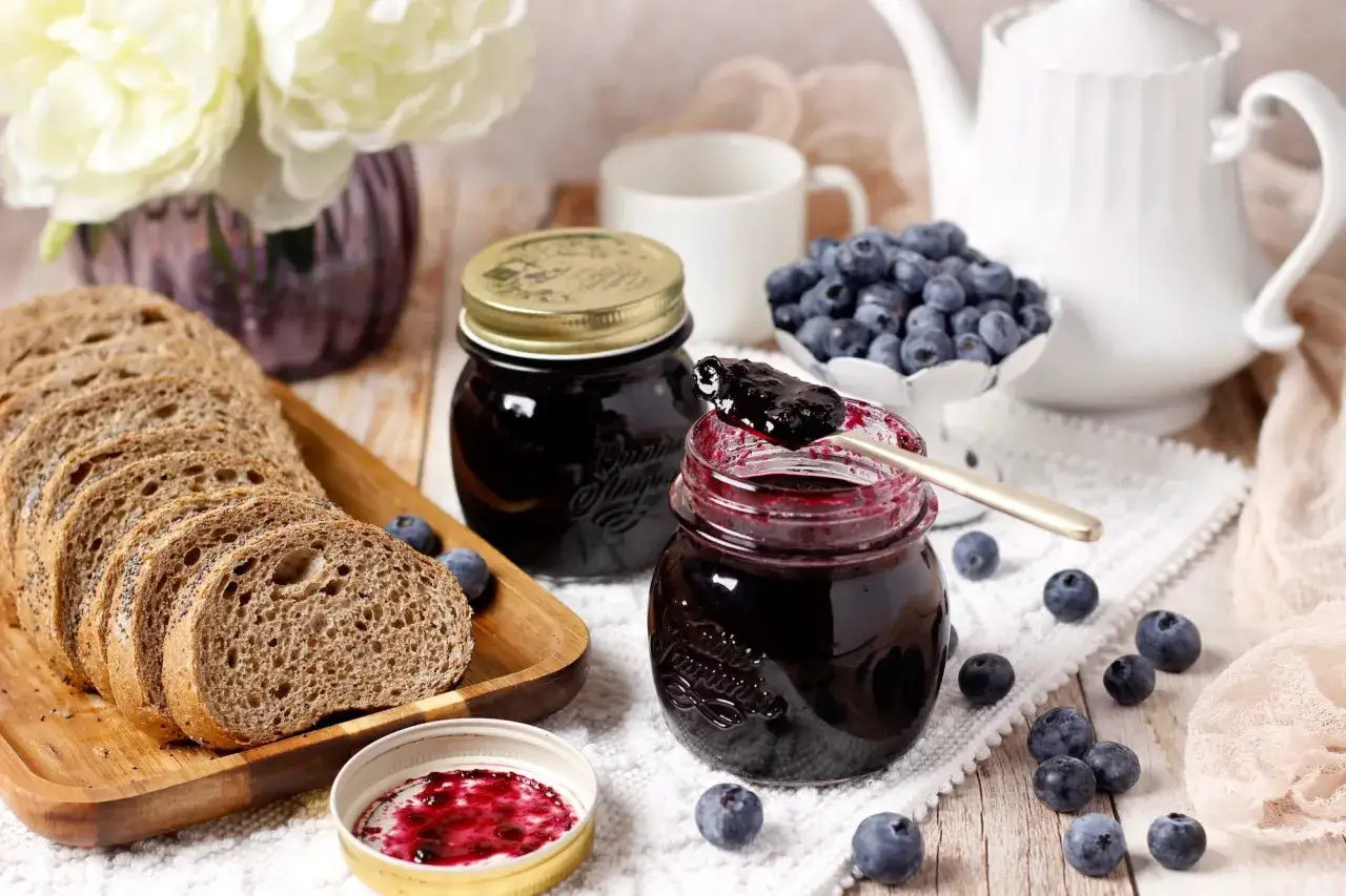Un petit-d&eacute;jeuner gourmand avec du pain aux c&eacute;r&eacute;ales, des myrtilles fra&icirc;ches et une d&eacute;licieuse confiture de myrtilles.