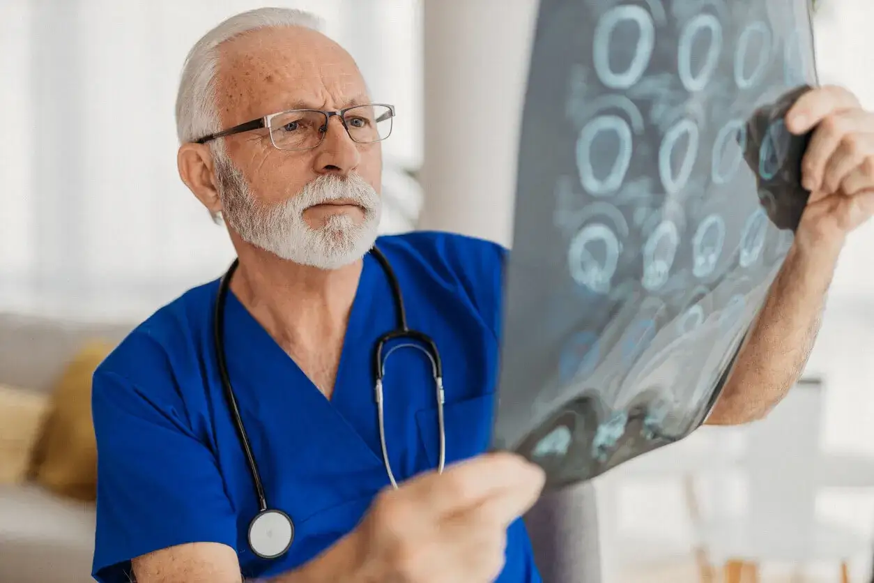 Doświadczony lekarz w niebieskim kitlu analizuje prześwietlenie mózgu, wykonując badanie neurologiczne.