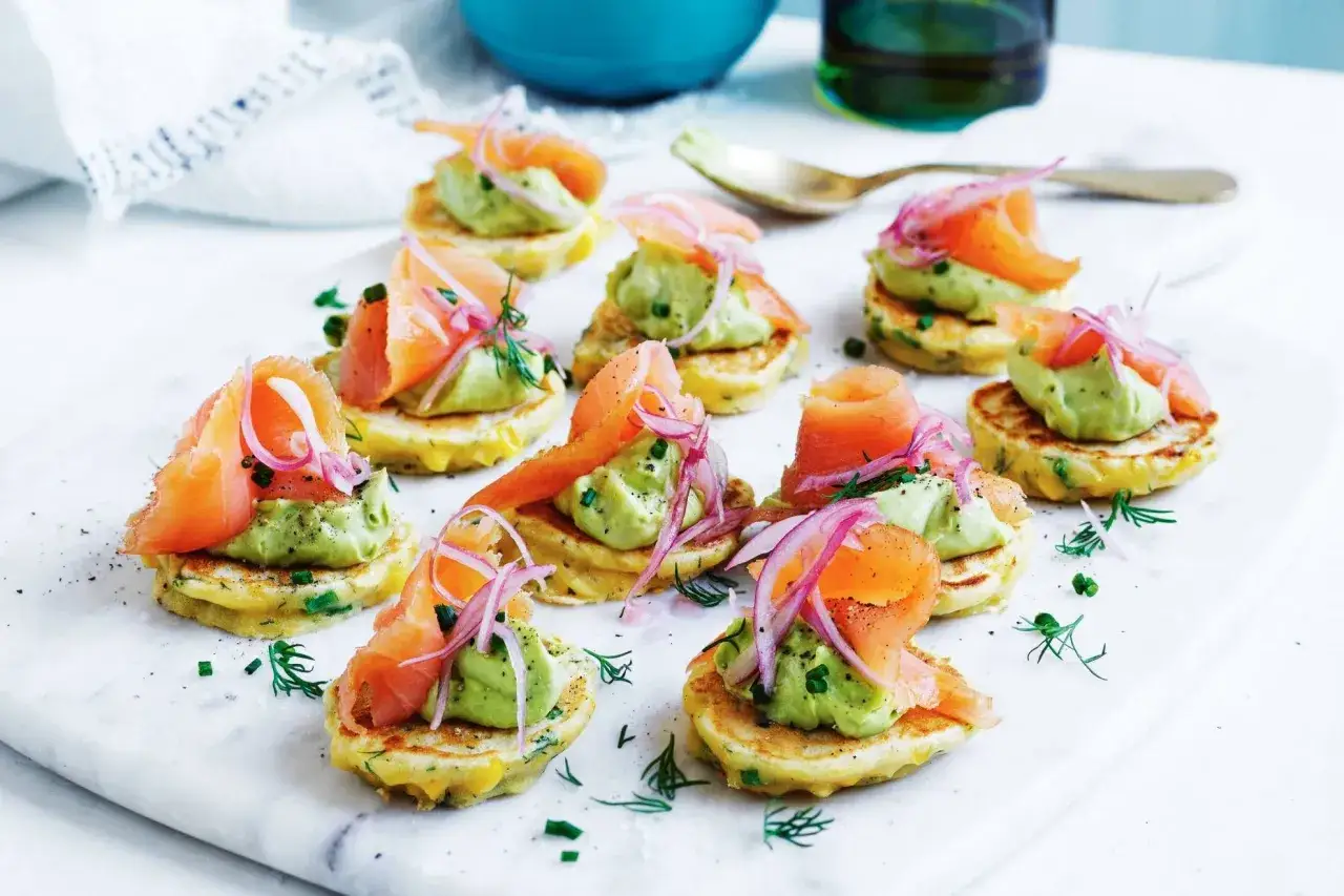 Kleine Pfannkuchen mit Avocado-Creme, R&auml;ucherlachs und roten Zwiebeln &ndash; ein k&ouml;stliches und gesundes Fingerfood.