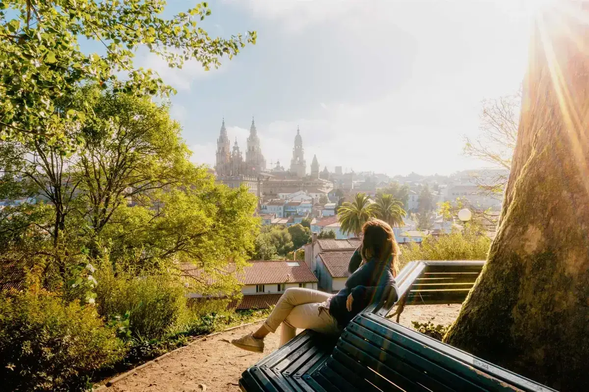 Mujer sentada en un banco, contemplando la ciudad y la catedral. Ella sueña con su próxima aventura, quiere viajar sola.