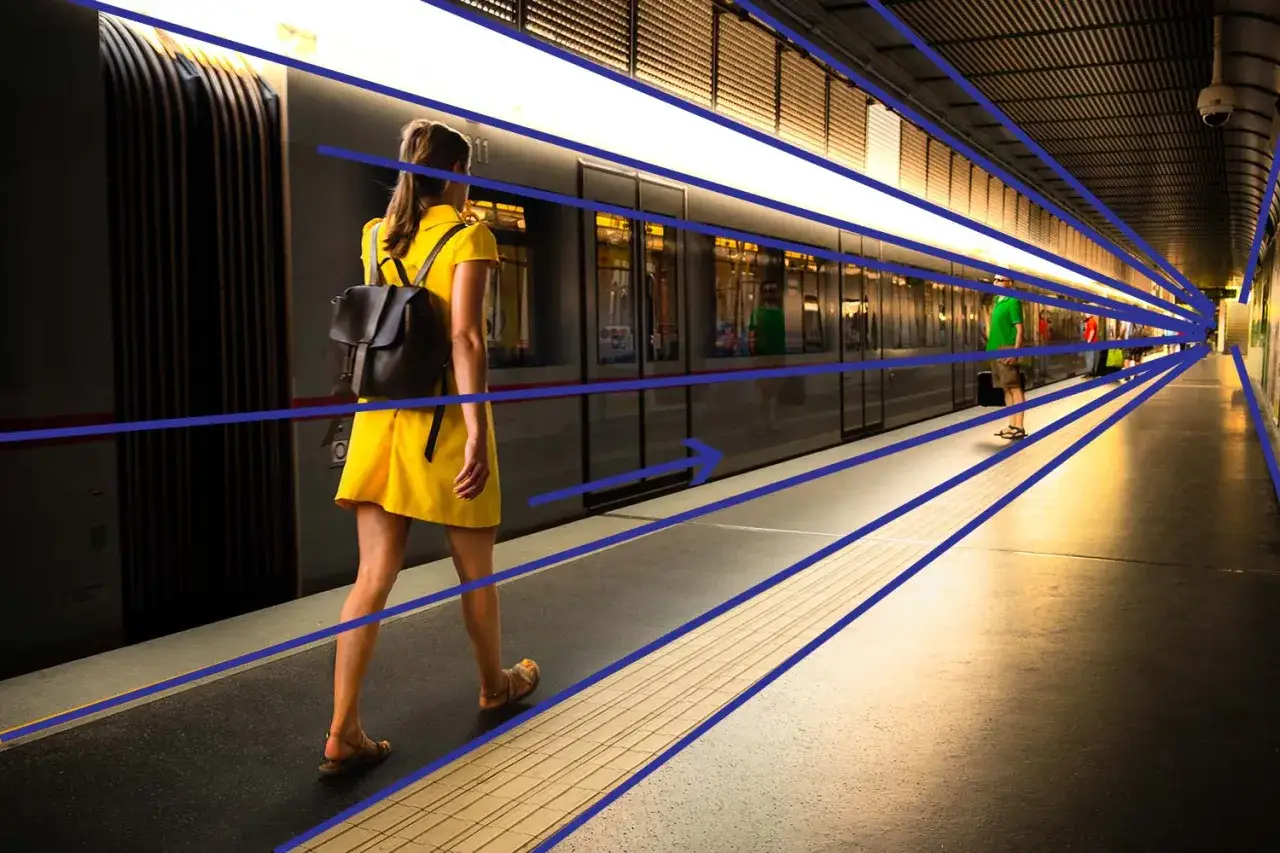 Kobieta w żółtej sukience na peronie metra. Linie perspektywiczne pokazują głębię, ciekawe ujęcie do nauki o fotografii.