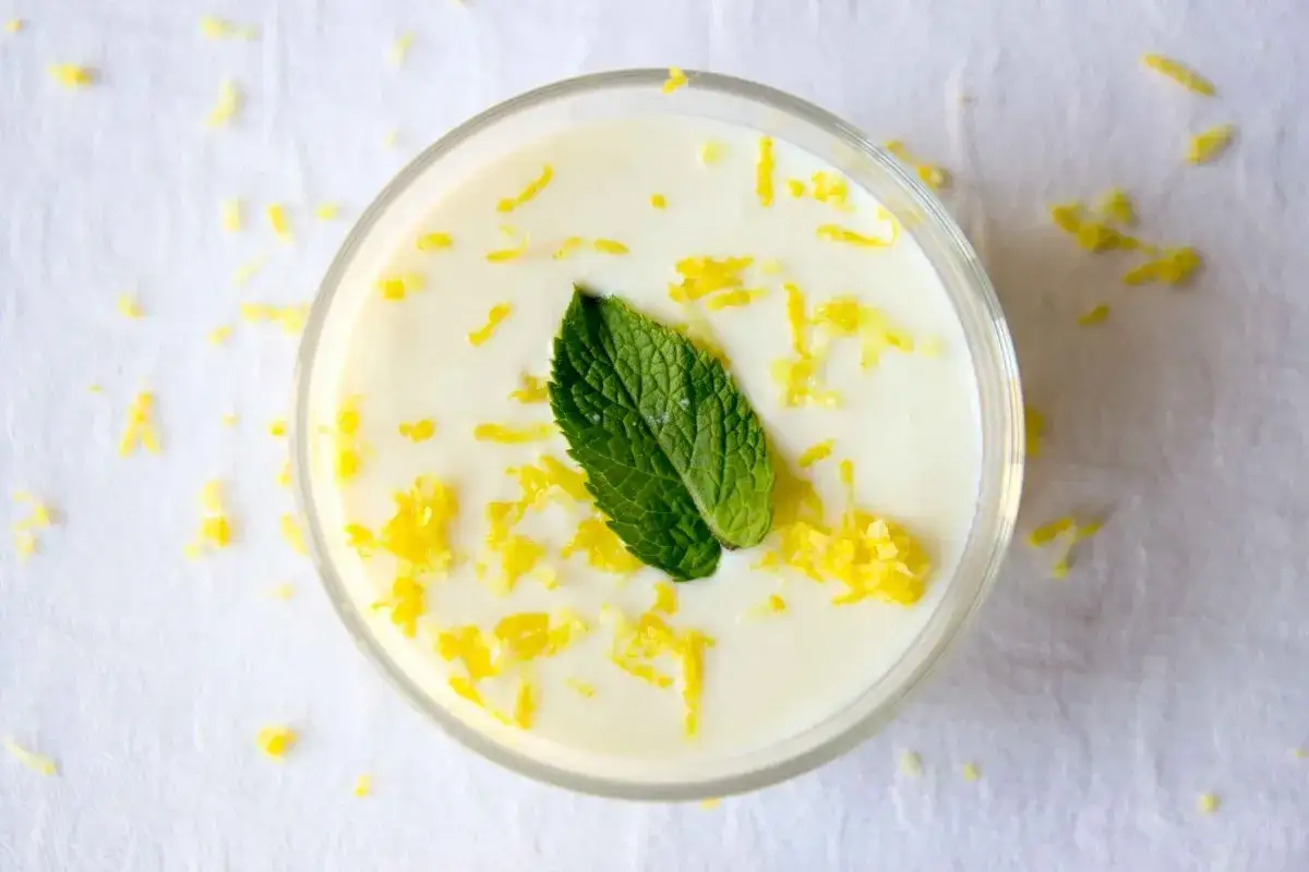 Delicioso mousse de limón Thermomix, decorado con ralladura de limón y una hoja de menta fresca.