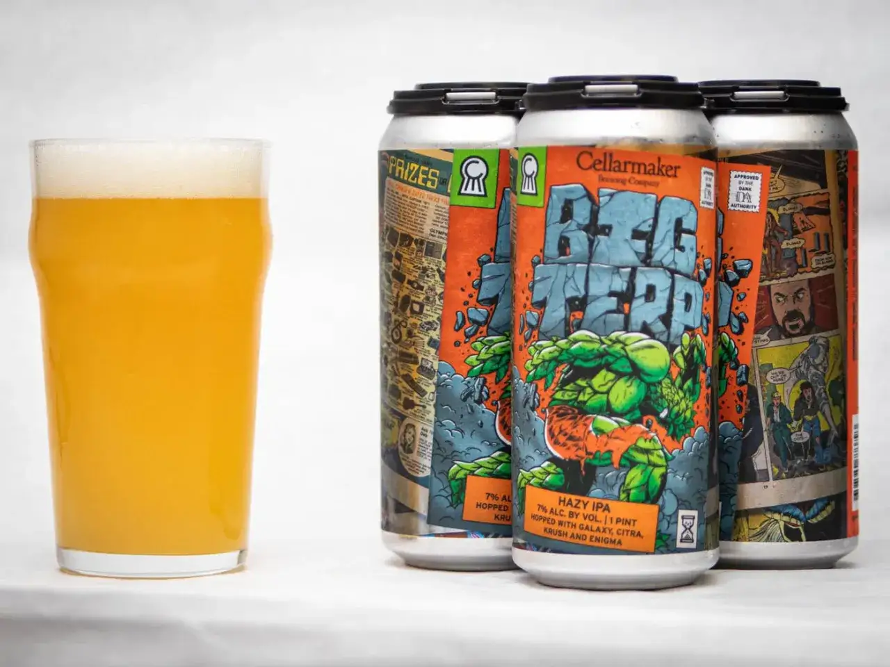 Szklanka złocistego piwa obok puszek Hazy IPA 