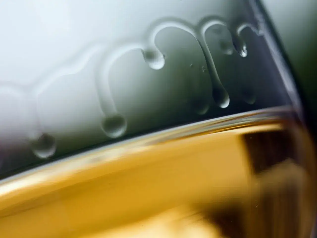 Tropfen auf Glas erinnern an ein Kirchenfenster, durch das goldenes Weinlicht f&auml;llt.