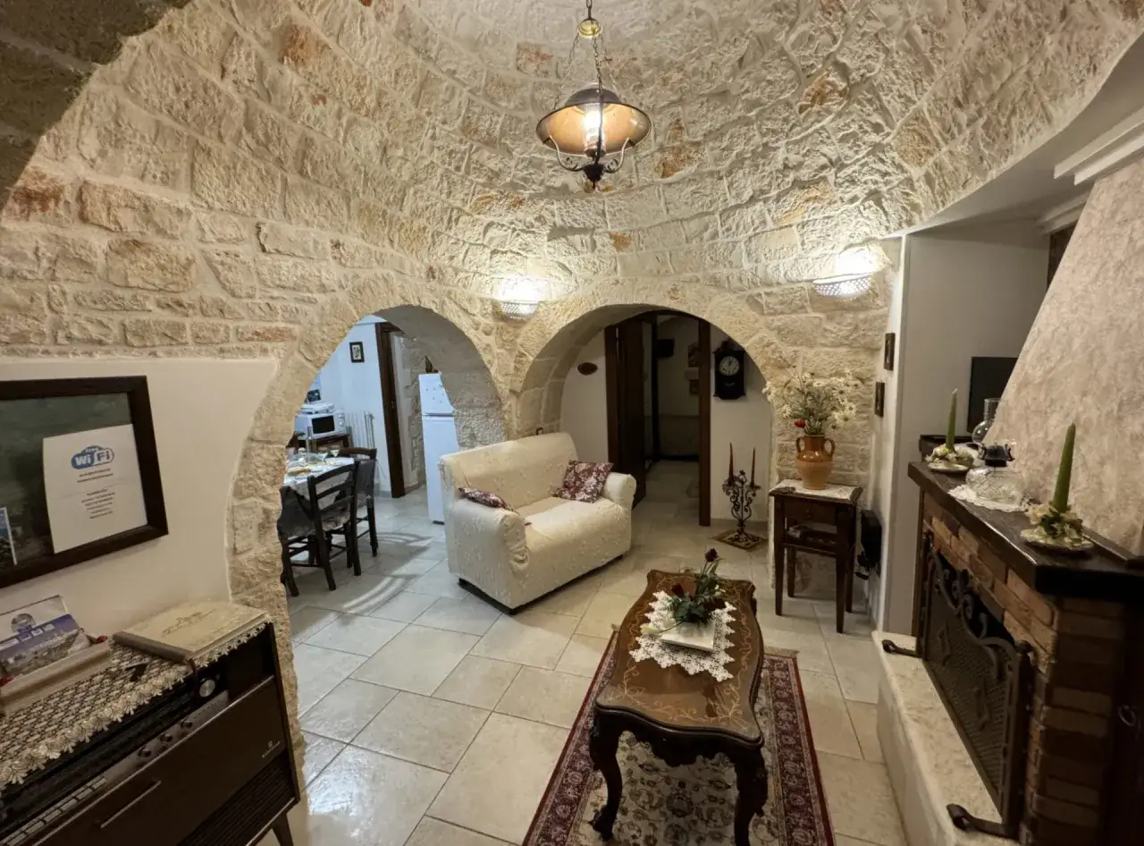 Wnętrze domków trulli z kamiennym sklepieniem, kanapą, stolikiem kawowym i kominkiem.