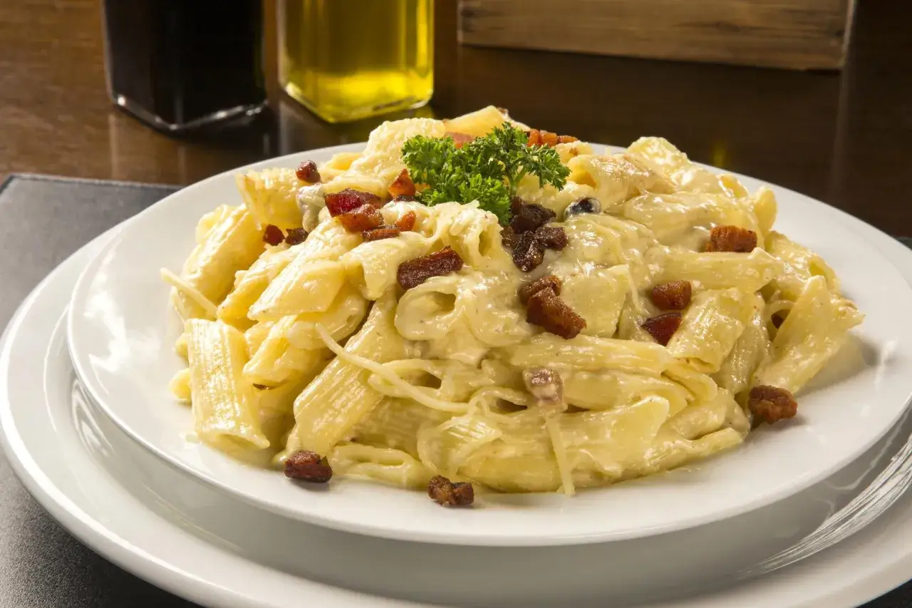 Penne rigate w kremowym sosie śmietanowo-serowym z kawałkami chrupiącego boczku i posypane parmezanem.