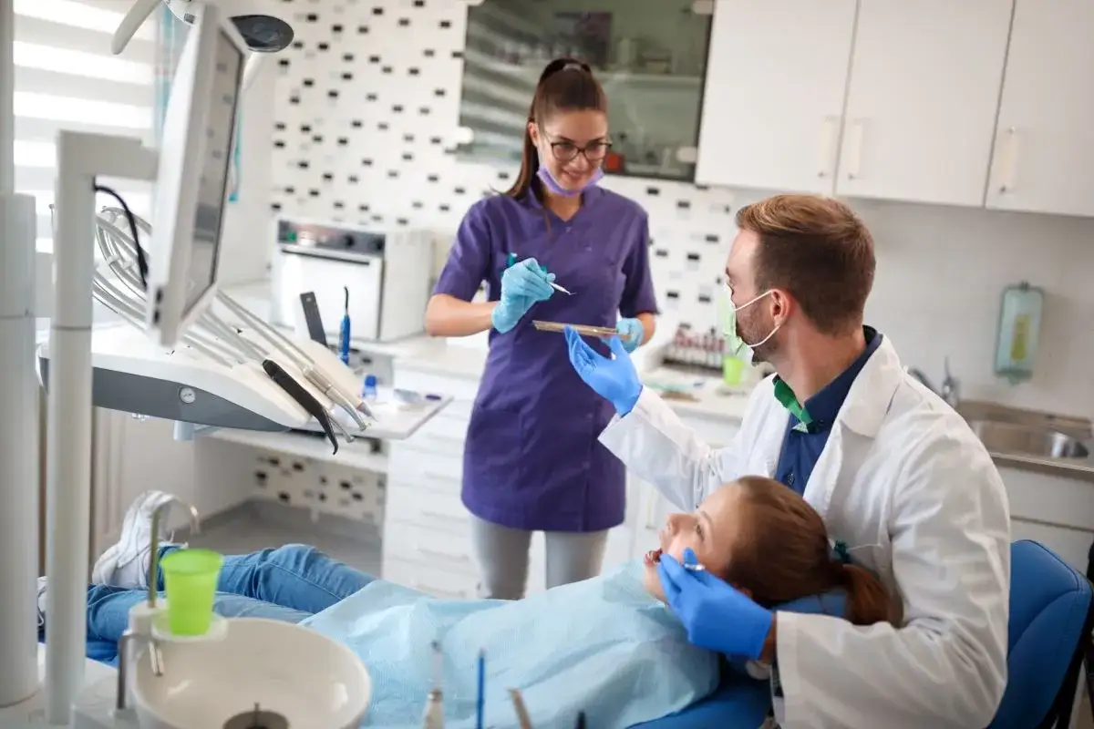 Dentysta i asystentka przygotowują się do zabiegu. Asystentka stomatologiczna online może pomóc w nauce.