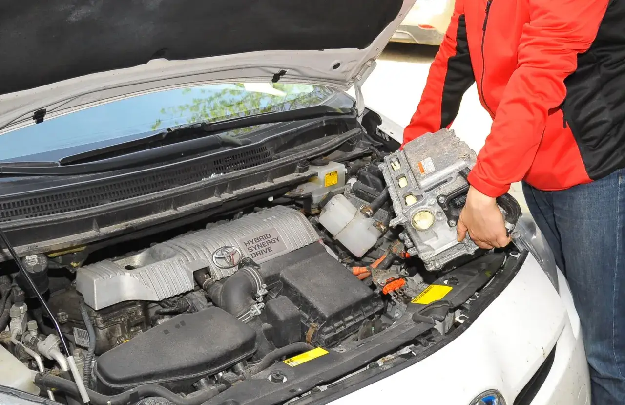 Osoba wyjmuje moduł sterujący z komory silnika Toyoty Auris Hybrid.