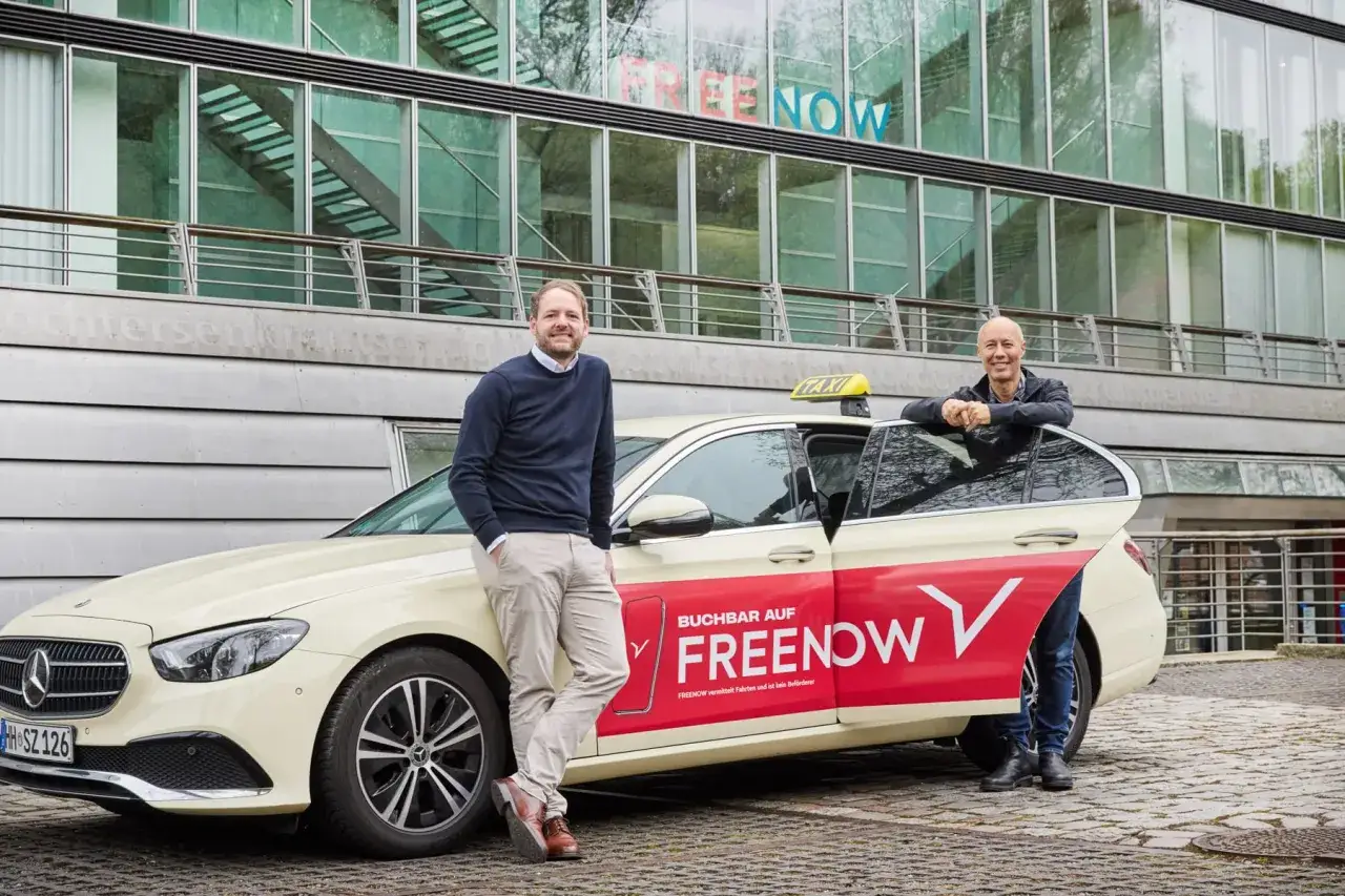 Zwei Männer stehen neben einem gelben Taxi mit der Aufschrift