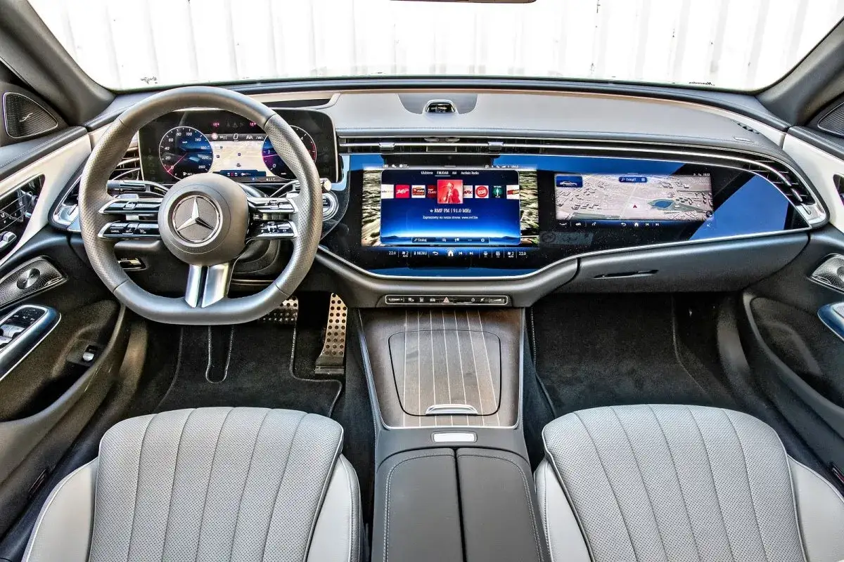 Wnętrze luksusowego mercedesa e220d z nowoczesnym ekranem MBUX, kierownicą i skórzanymi fotelami.