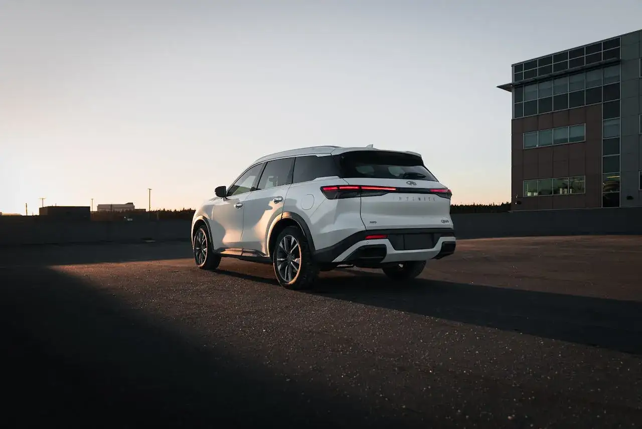 Biały SUV Infiniti na parkingu. Rozważasz zakup samochodu na wynajem? Sprawdź koszty i porównaj oferty.