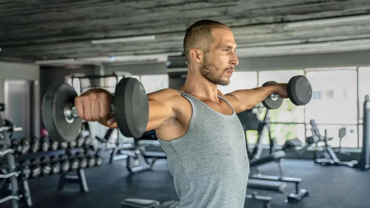 Mężczyzna wykonuje ćwiczenia na biceps z hantlami, budując siłę i masę mięśniową w siłowni.