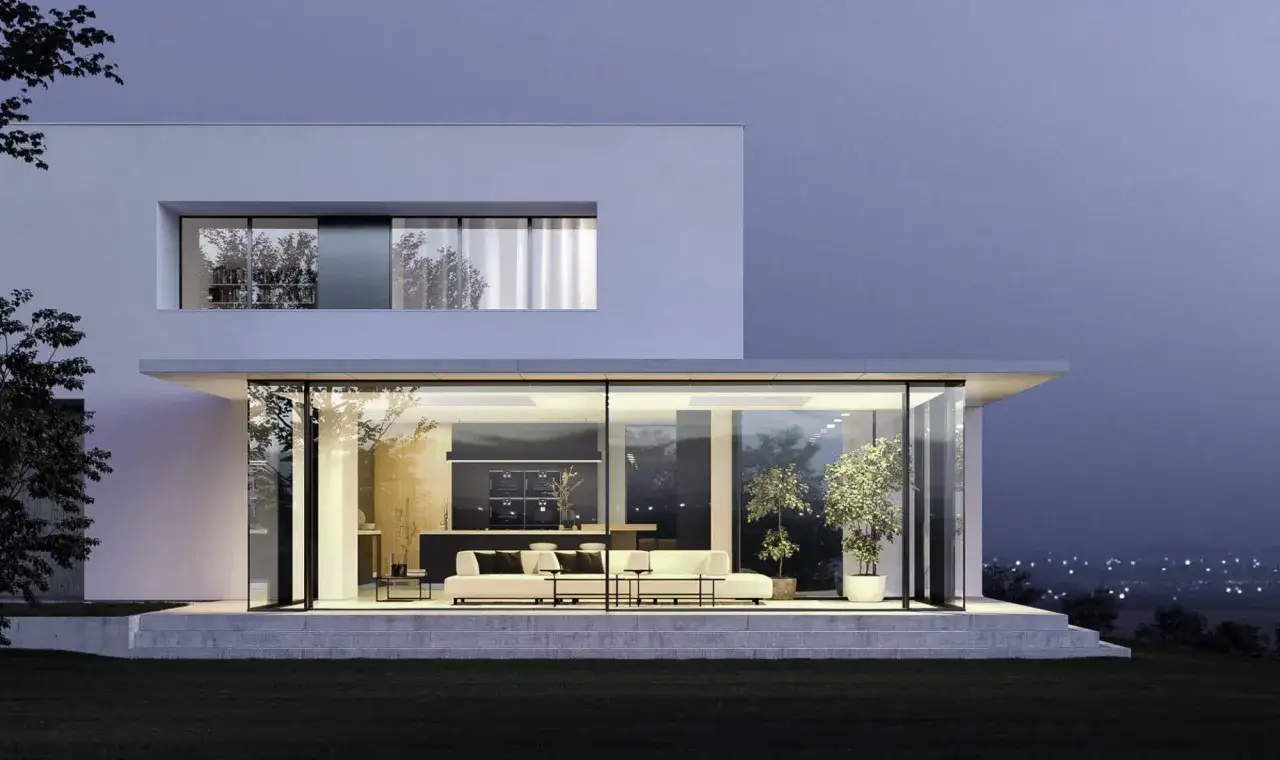 Une maison design moderne avec de grandes baies vitr&eacute;es illumin&eacute;es, r&eacute;v&eacute;lant un salon et une cuisine &eacute;pur&eacute;s.