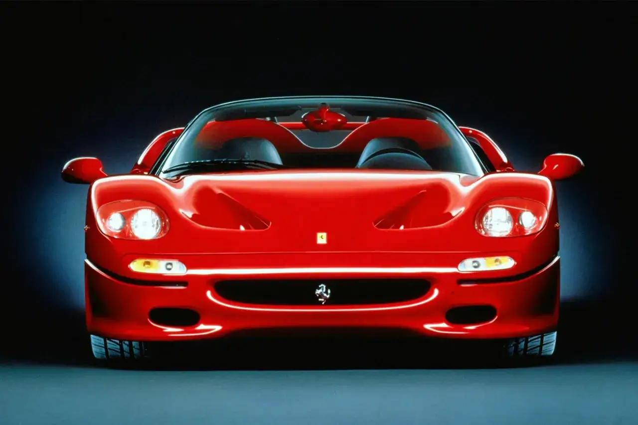 Czerwone Ferrari F50 z otwartym dachem, z bliska, z reflektorami skierowanymi do przodu.