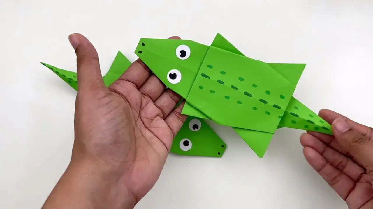 Grüne Papierkrokodile, die zum Schnappi falten bereit sind, mit großen Augen und Tupfen.
