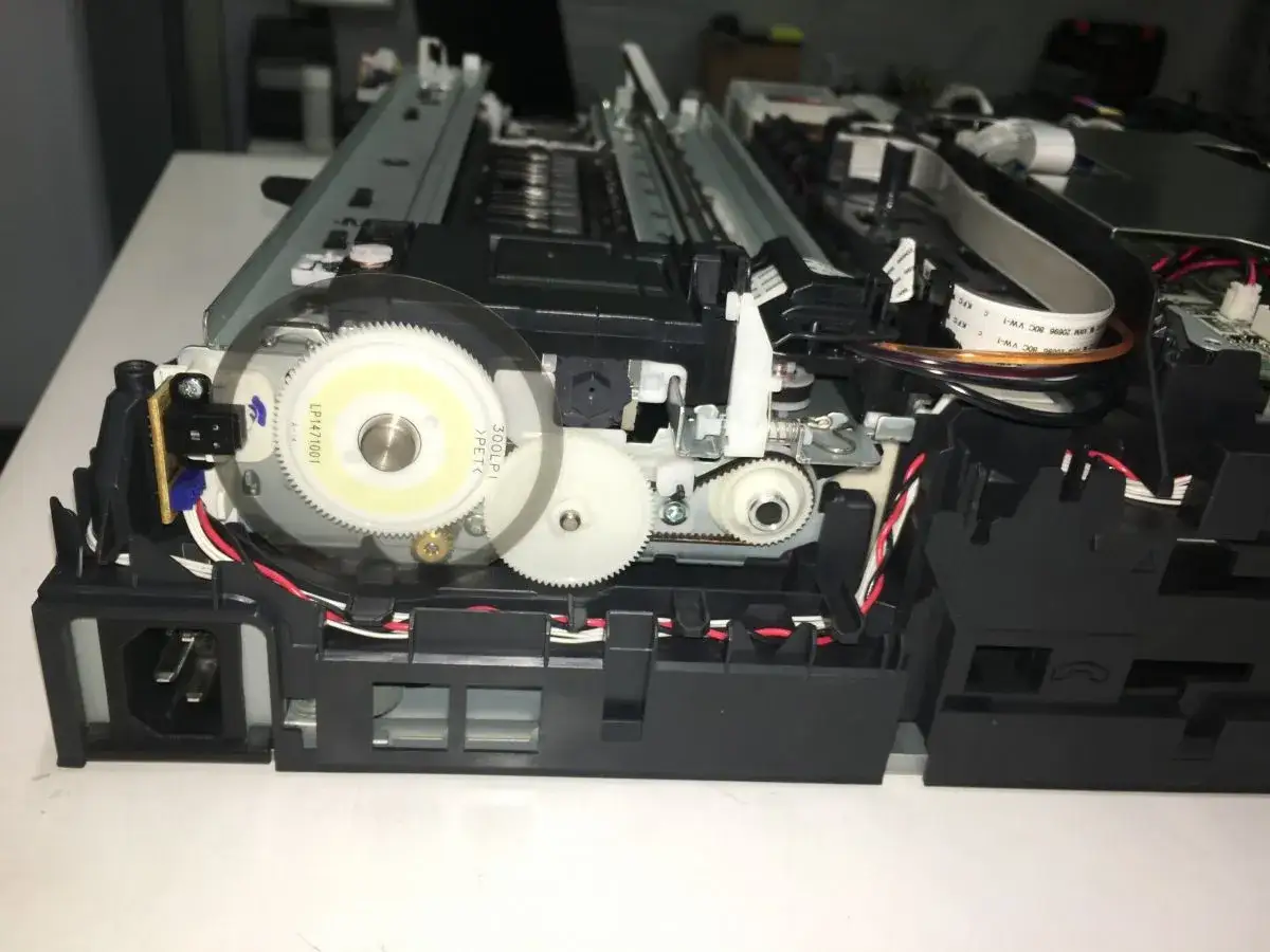 Wnętrze drukarki Brother z widocznymi zębatkami i taśmami. Prawdopodobnie problem z mechanizmem napędowym, kt&oacute;ry powoduje błąd drukarki Brother.