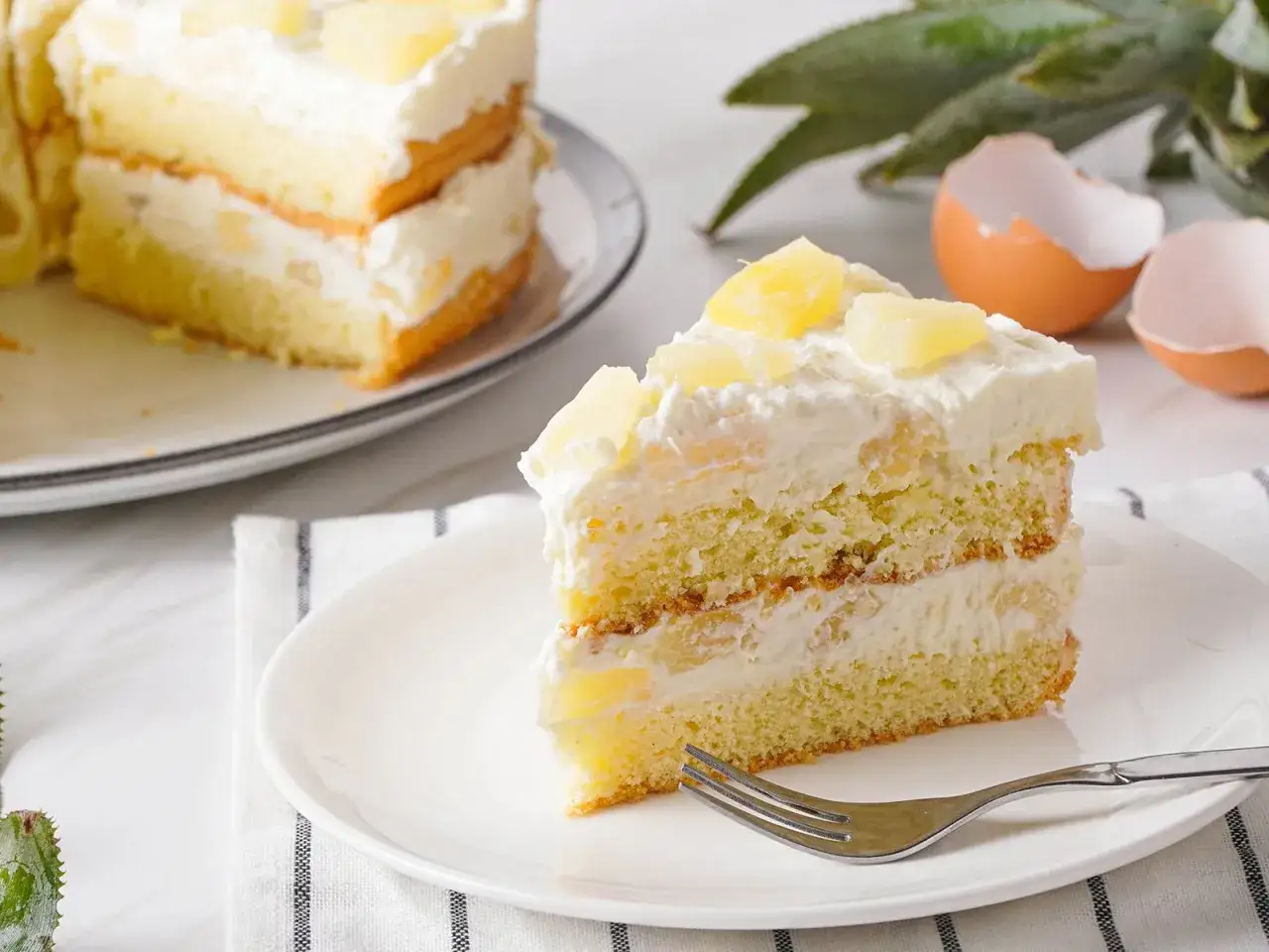 Ein saftiges St&uuml;ck Ananas Torte mit Sahne und Ananasst&uuml;cken, bereit zum Genuss.