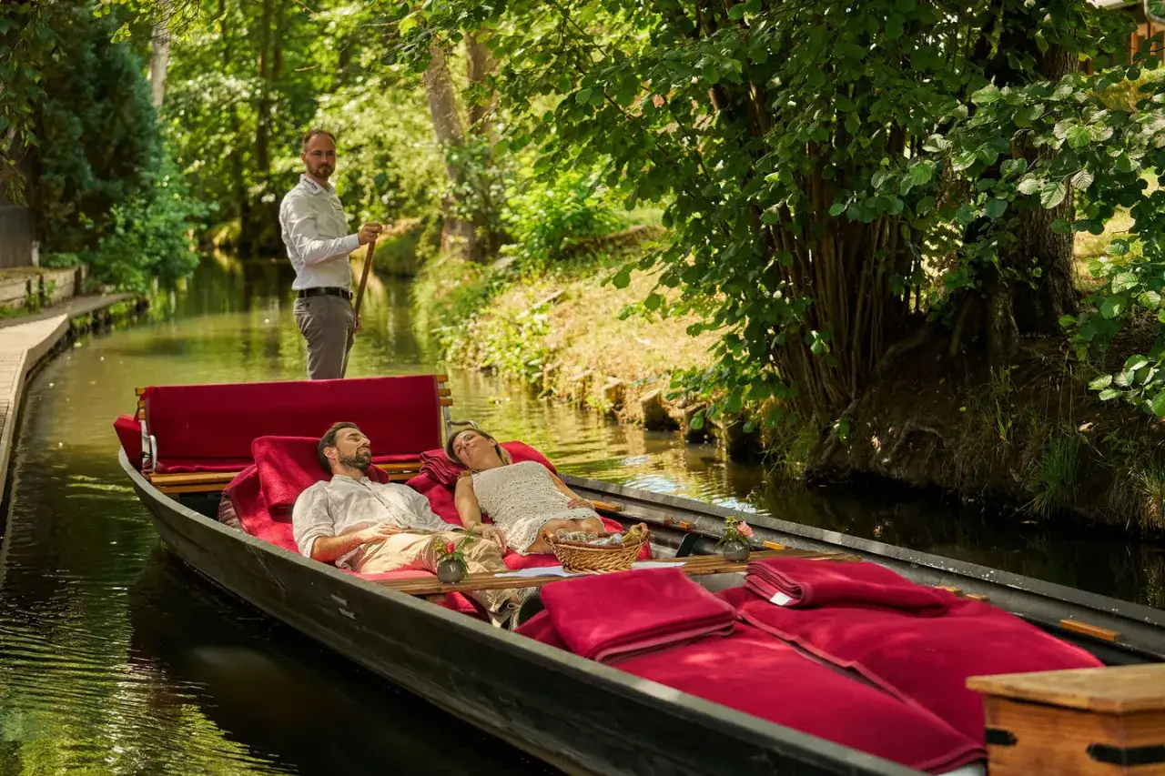 Ein Paar entspannt auf einer Kahnfahrt im Spreewald, w&auml;hrend ein F&auml;hrmann rudert. Perfekte ausflugsziele spreewald f&uuml;r Erholung.