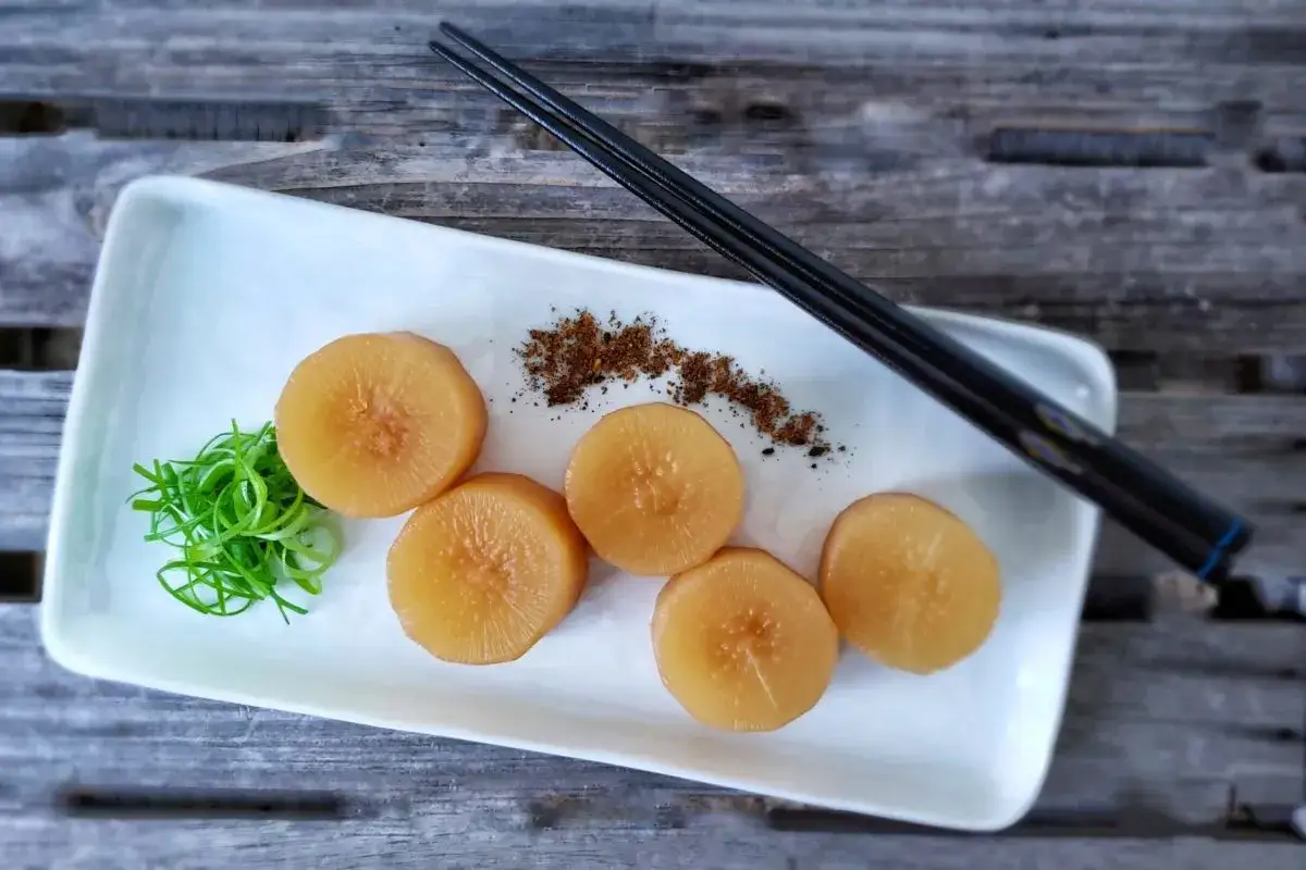 Plasterki rzodkwi do sushi, podane z zieloną cebulką i przyprawami.