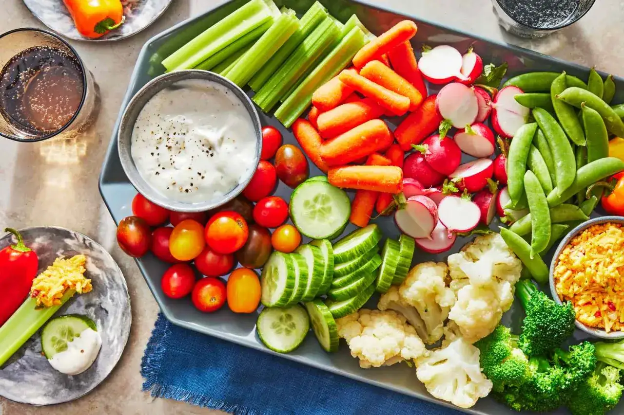 Plateau de crudités colorées : carottes, céleri, radis, tomates, concombres, pois gourmands, brocolis, chou-fleur. Idéal pour une recette de crudités pour buffet.