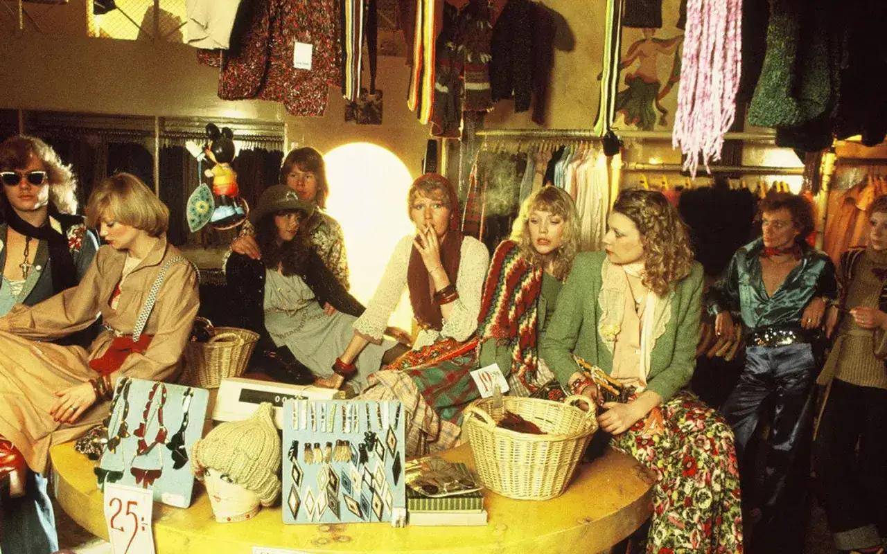 En grupp unga m&auml;nniskor i en retrobutik. En kvinna r&ouml;ker, en annan har p&aring; sig jeans gul och bl&aring;.