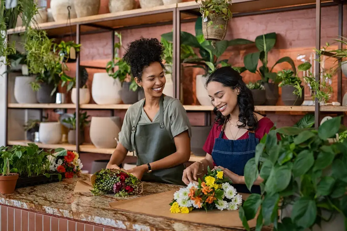 Deux fleuristes souriantes cr&eacute;ent des bouquets. Un m&eacute;tier artistique bien pay&eacute; qui embellit le quotidien.