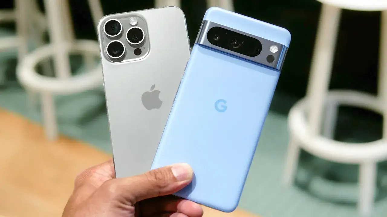 Dłoń trzyma dwa smartfony: srebrnego iPhone'a i błękitnego Pixela. Oba telefony potrzebują dobrego antywirusa na telefon.