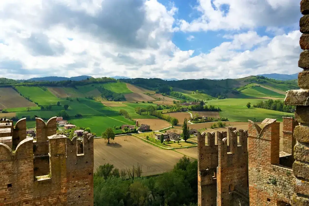 Vista panoramica dalle mura di un castello su colline verdi e campi coltivati, con case sparse. Un paesaggio incantevole nei dintorni di Bagnoli del Trigno.