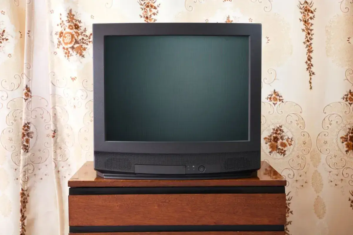 Stary telewizor na drewnianej szafce. Zastanawiasz się, od jakiego wieku nie płaci się abonamentu RTV?