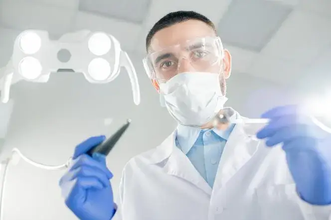 Pacjent w poczekalni u dentysty w maseczce i bez
