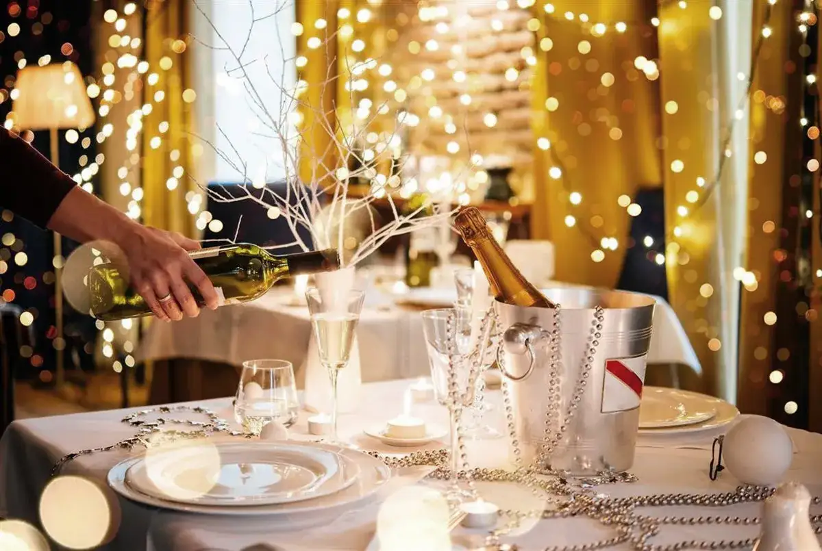 Mesa festiva lista para celebrar. Ideas para decorar un bar para Navidad con luces cálidas, copas, champán y un toque de elegancia.