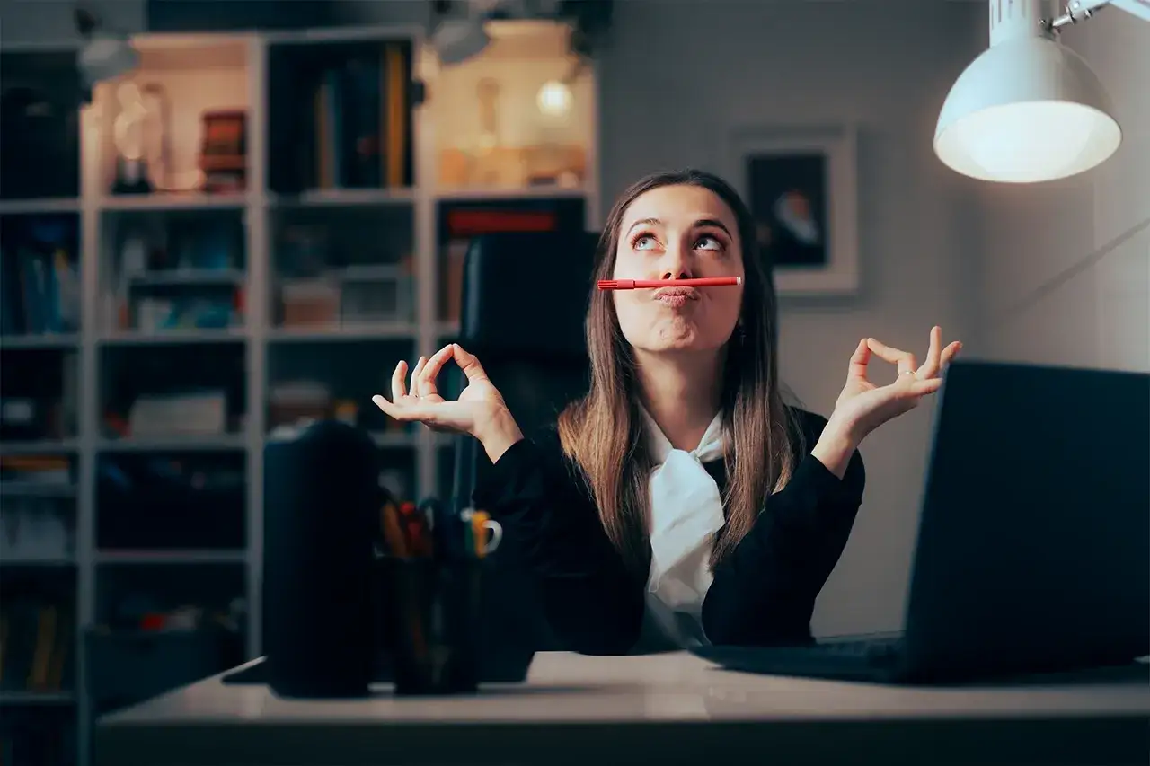 Kobieta z kredką w ustach, w pozie medytacyjnej, zastanawia się, prokrastynacja co to.