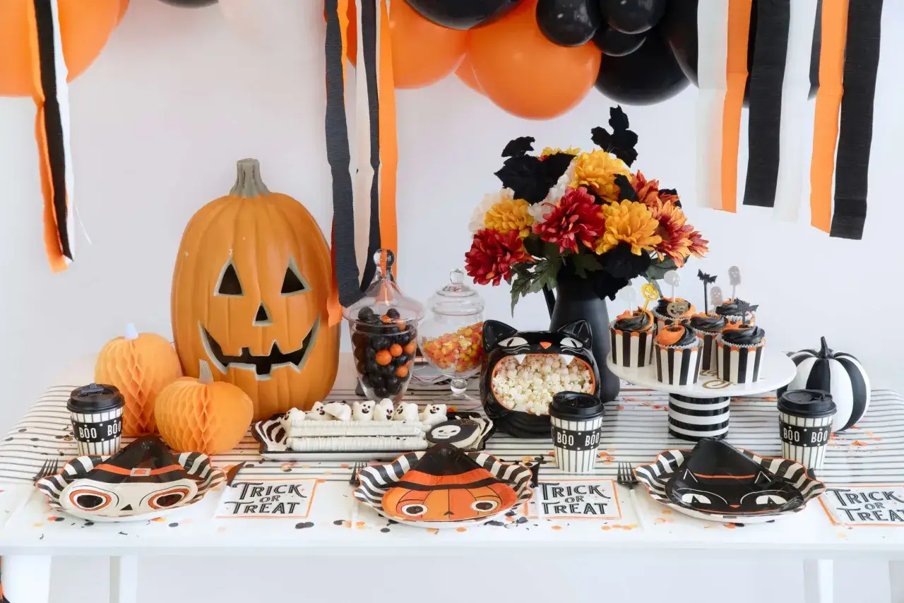Table pr&ecirc;te pour organiser une soir&eacute;e d'Halloween : citrouille, bonbons, cupcakes, et d&eacute;corations effrayantes.