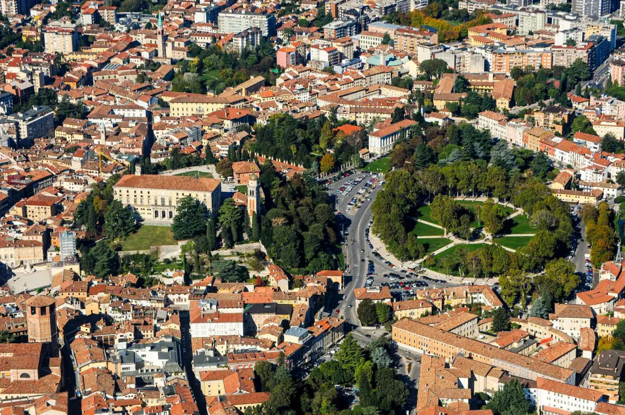 Vista aerea di una città con tetti rossi, un parco verde e un edificio storico. Un assaggio di cosa vedere in Friuli Venezia Giulia.